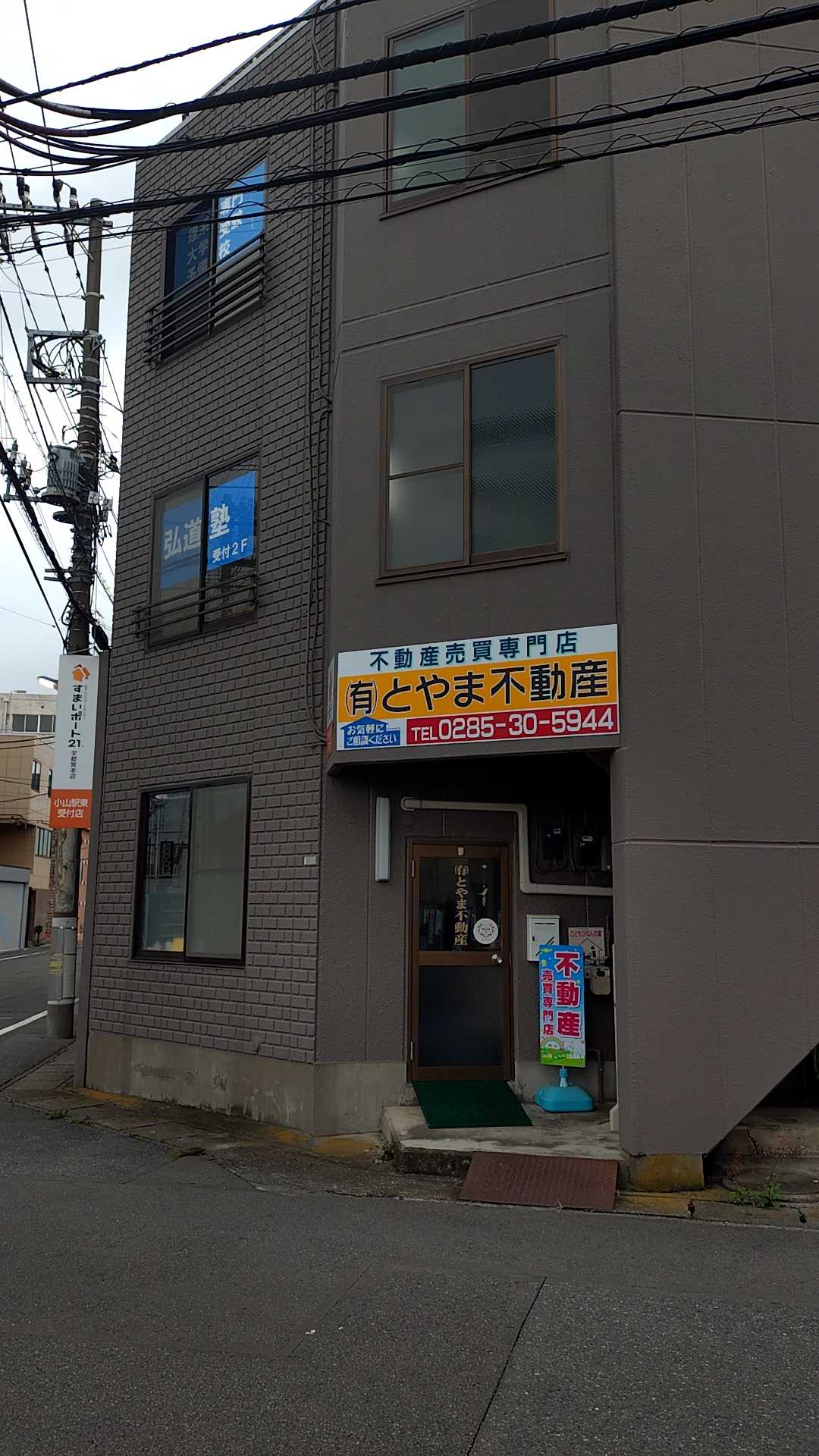 1階がとやま不動産で、右側に2階の弘道塾受付へ繋がる外階段がある海老沼ビルの外観